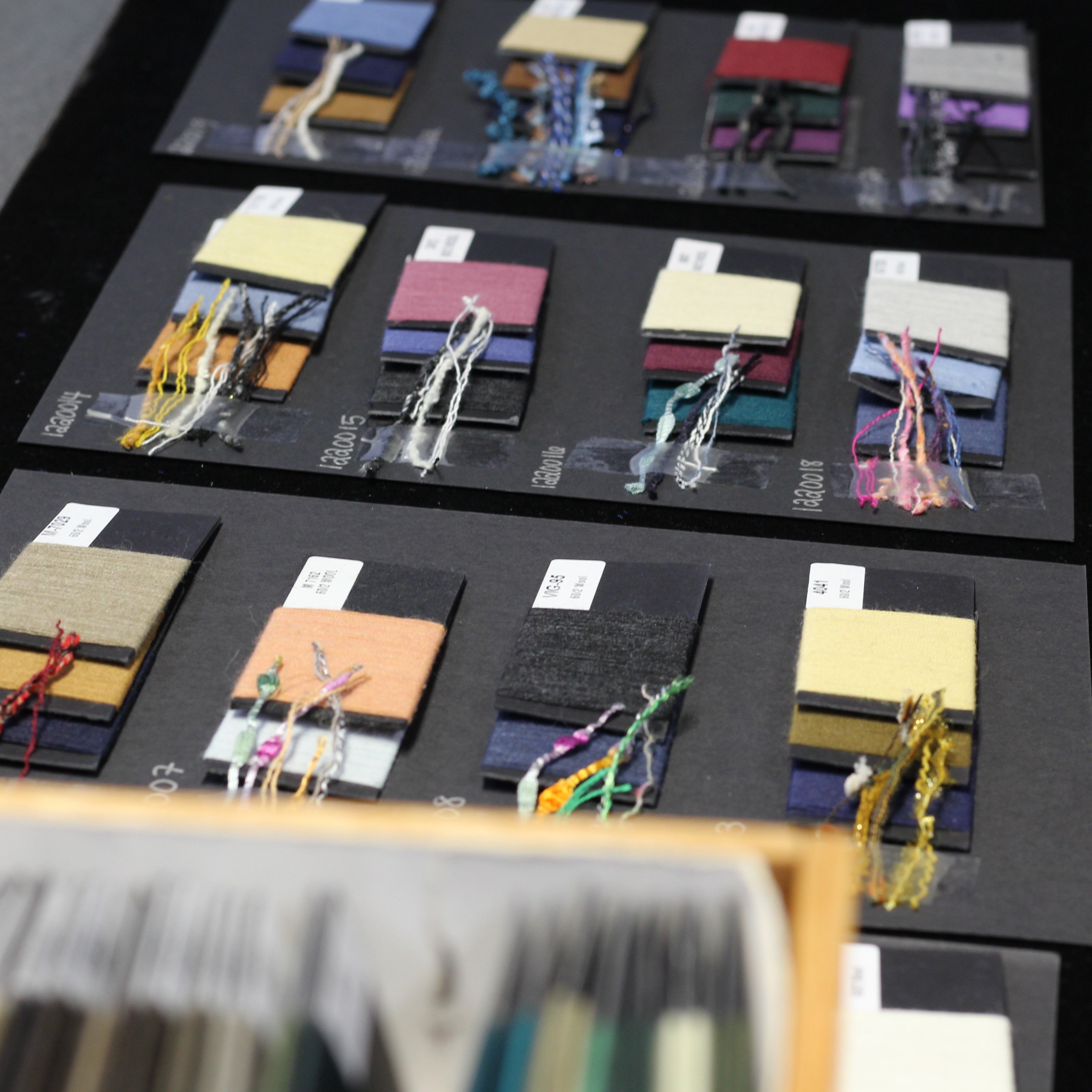Variety of threads for tailoring, displayed on a table against a black backdrop for enhanced visibility.